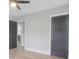 Bedroom with wood-look floors, neutral walls, dark doors and ceiling fan. Bathroom is visible in the background at 1715 N Alexander Rd, Tampa, FL 33603