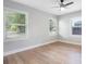Bright bedroom featuring wood-look floors, neutral walls, ceiling fan, and ample natural light from windows at 1715 N Alexander Rd, Tampa, FL 33603