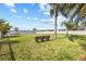Spacious backyard features lush lawn, a bench under the palm trees, and stunning water views at 1858 Mira Lago Cir, Ruskin, FL 33570