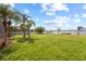 Expansive backyard with green grass, palm trees, and a white picket fence offers serene water views at 1858 Mira Lago Cir, Ruskin, FL 33570
