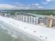 Aerial view showcasing a white sand beach, waterfront condos, and nearby river at 18650 Gulf Blvd # 203, Indian Shores, FL 33785