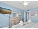 Well-lit bedroom featuring a dresser with a TV, a ceiling fan and blue walls at 18650 Gulf Blvd # 203, Indian Shores, FL 33785
