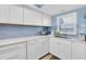 A kitchen with white cabinets, modern appliances, stainless steel sink, and blue accent tiles at 18650 Gulf Blvd # 203, Indian Shores, FL 33785
