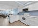 Bright kitchen with white cabinets, stainless steel microwave, and open view to the living area and ocean at 18650 Gulf Blvd # 203, Indian Shores, FL 33785