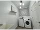 Well-lit laundry room featuring a washer, dryer, utility sink, and stylish wallpaper accent at 18657 Obregan Dr, Spring Hill, FL 34610