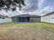 Wide view of the backyard with a screened in lanai and white fencing at 1919 Oswego Dr, Holiday, FL 34691