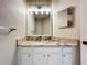 Bright bathroom vanity featuring a granite countertop, white cabinets, and modern fixtures with a large mirror at 1919 Oswego Dr, Holiday, FL 34691