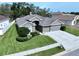 Beautiful single-story home featuring a manicured lawn, a three-car garage, and mature landscaping at 1919 Oswego Dr, Holiday, FL 34691