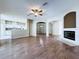 Open living room with a ceiling fan, fireplace, wood floors, and access to the kitchen at 1919 Oswego Dr, Holiday, FL 34691