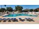 Community pool with multiple lounge chairs and blue umbrellas for relaxing by the water at 1919 Oswego Dr, Holiday, FL 34691