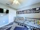 Cozy Bedroom features two cribs, a TV on the wall, and nautical themed decor, creating a playful space at 21626 Rosewood Ct, Lutz, FL 33549