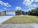 Charming blue home featuring an attached two-car garage, well-manicured lawn, and mature palm trees at 21626 Rosewood Ct, Lutz, FL 33549