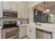 Open kitchen featuring white cabinets, stainless steel appliances, and accent wall at 2221 Soho Bay Ct, Tampa, FL 33606