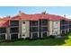 Exterior view of building featuring screened in porches, red tile roof, and lush green grass at 2400 Feather Sound Dr # 635, Clearwater, FL 33762