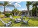 The backyard features a fire pit with chairs, lush green grass, palm trees, and a screened lanai at 26701 Winged Elm Dr, Wesley Chapel, FL 33544