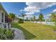 Expansive, well-manicured backyard featuring lush green grass, a white picket fence, and landscaping under a partly cloudy sky at 26701 Winged Elm Dr, Wesley Chapel, FL 33544