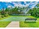 Outdoor basketball court with a green playing surface, a net, surrounding landscaping, and a bench at 26701 Winged Elm Dr, Wesley Chapel, FL 33544