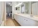 Bathroom with double sinks and white cabinets with a view into the bedroom with a hanging macrame chair at 26701 Winged Elm Dr, Wesley Chapel, FL 33544