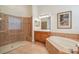 Bathroom featuring a shower with a glass surround, soaker tub, and oak cabinetry at 26701 Winged Elm Dr, Wesley Chapel, FL 33544
