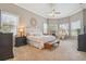 Comfortable carpeted bedroom with tray ceilings, a ceiling fan, and natural light from a wall of windows at 26701 Winged Elm Dr, Wesley Chapel, FL 33544