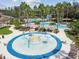 Aerial view of a community pool area with multiple pools, a splash pad, lounge chairs, and tropical landscaping at 26701 Winged Elm Dr, Wesley Chapel, FL 33544