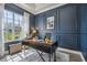 Stylish office with a modern desk, large window, and elegant navy blue paneled walls at 26701 Winged Elm Dr, Wesley Chapel, FL 33544