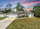 Beautiful sunset view of a cozy single-story home with lush tropical landscaping and ample parking space at 2675 Cherokee St, North Port, FL 34286