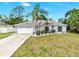 Single story home with an attached two car garage and a long driveway, complemented by tropical landscaping at 2675 Cherokee St, North Port, FL 34286