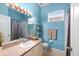 Bright bathroom with blue walls, a vanity with a sink, toilet, shower and a window above the toilet at 2808 Abbey Grove Dr, Valrico, FL 33594