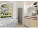 Bright bathroom with a large tub under a window and a separate vanity area at 2808 Abbey Grove Dr, Valrico, FL 33594