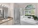 Bright bathroom featuring a walk-in shower, soaking tub under an arched window, and neutral-toned vanity at 2808 Abbey Grove Dr, Valrico, FL 33594