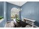 Dining area featuring an arched window, chandelier, and a rustic wooden table, complemented by light blue walls at 2808 Abbey Grove Dr, Valrico, FL 33594