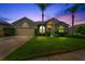 Inviting home at twilight featuring professional landscaping, mature palm trees, and a well-manicured lawn at 2808 Abbey Grove Dr, Valrico, FL 33594