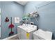 Well-lit laundry room with washer, dryer, utility sink and storage shelving at 2808 Abbey Grove Dr, Valrico, FL 33594