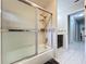 Bathroom features a shower/tub with glass doors and modern finishes; view into adjacent hallway at 30456 Willow Bank Ave, Brooksville, FL 34602