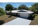 Well-maintained single-story home with a white metal roof, gray exterior, and a spacious driveway leading to a two-car garage at 30456 Willow Bank Ave, Brooksville, FL 34602