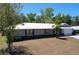Charming single-story home featuring a light gray exterior, white metal roof, and an attached two-car garage at 30456 Willow Bank Ave, Brooksville, FL 34602