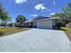 Well-maintained single-story home with a white metal roof, gray exterior, and a spacious driveway leading to a two-car garage at 30456 Willow Bank Ave, Brooksville, FL 34602