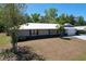 Charming single-story home featuring a light gray exterior, white metal roof, and an attached two-car garage at 30456 Willow Bank Ave, Brooksville, FL 34602