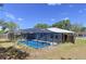 Inviting screened-in pool with clear blue water, surrounded by a spacious patio area and lush green landscaping at 30456 Willow Bank Ave, Brooksville, FL 34602