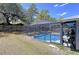 Inviting screened-in pool with clear blue water, surrounded by a spacious patio area and lush green landscaping at 30456 Willow Bank Ave, Brooksville, FL 34602