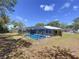 Inviting screened-in pool with clear blue water, surrounded by a spacious patio area and lush green landscaping at 30456 Willow Bank Ave, Brooksville, FL 34602