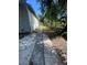 Cracked driveway on the side of the house, leading to the backyard, with trees and vegetation surrounding at 3515 E 8Th Ave, Tampa, FL 33605