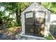 Storage shed with double doors, located in the backyard, surrounded by greenery and trees at 3515 E 8Th Ave, Tampa, FL 33605