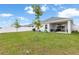 Grassy backyard featuring an open patio area, young trees, and partial toys at 35519 Bellington Blvd, Zephyrhills, FL 33541