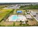 Aerial view of community pool, playground, clubhouse, and parking surrounded by trees at 35519 Bellington Blvd, Zephyrhills, FL 33541