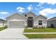 Charming single-story home with a gray exterior, a two-car garage, and a well-manicured lawn at 35519 Bellington Blvd, Zephyrhills, FL 33541