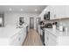 Modern kitchen with white cabinets, stainless steel appliances, quartz counters, and large center island with sink at 35519 Bellington Blvd, Zephyrhills, FL 33541