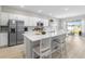 Modern kitchen with white cabinets, stainless steel appliances, quartz counters, and large center island with barstool seating at 35519 Bellington Blvd, Zephyrhills, FL 33541