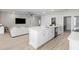 Open concept kitchen with white cabinets, quartz counters, and stainless appliances is bright and airy with hardwood floors at 35519 Bellington Blvd, Zephyrhills, FL 33541